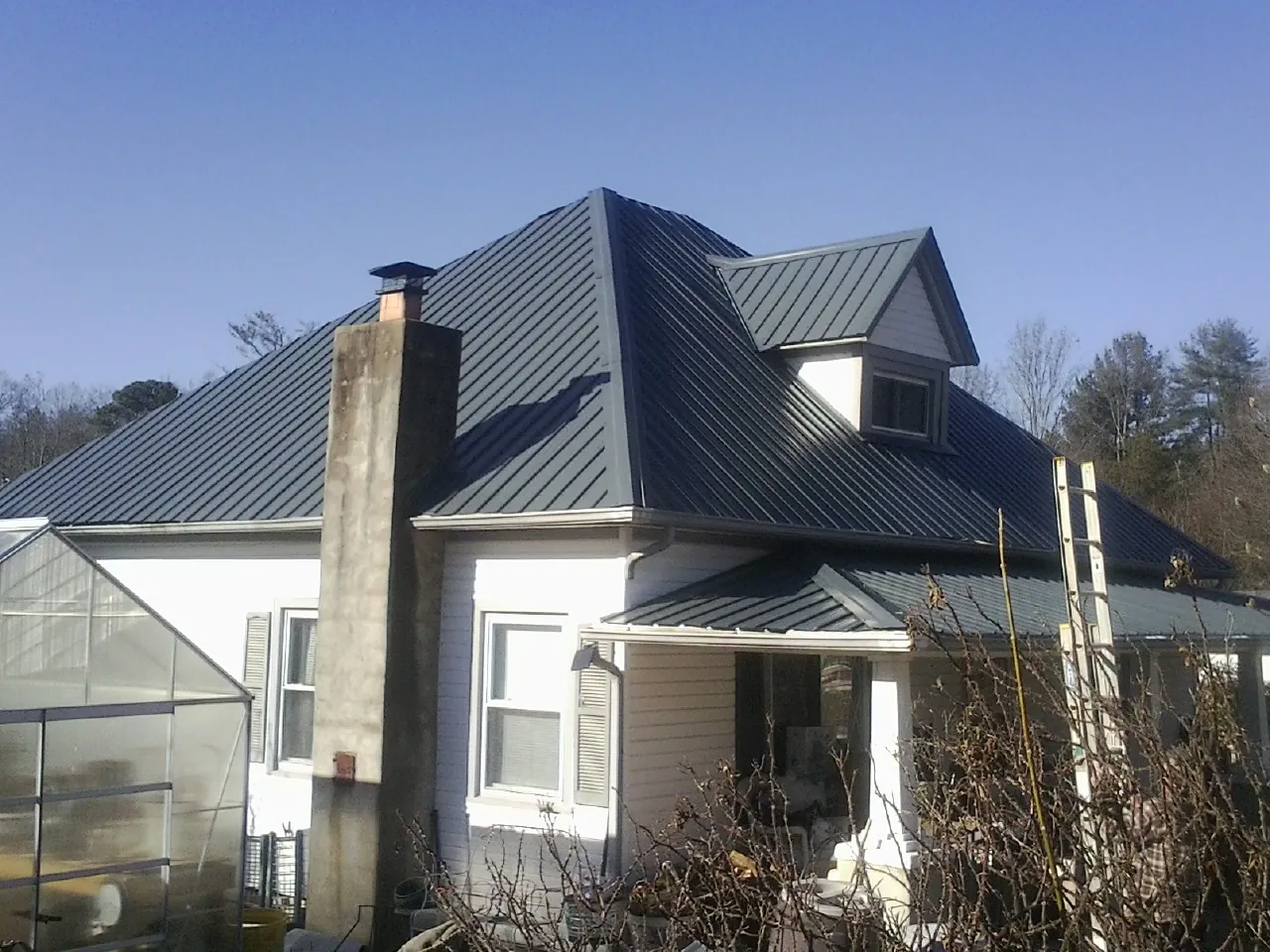 Dark blue standing seam metal roof on a white farmhouse with dormer — Slate & Tile Roof Repair by Roofing Brothers in Yadkinville