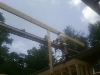 Carpenter setting a ridge beam over a new addition frame — Ice Dam Removal by Roofing Brothers in Yadkinville