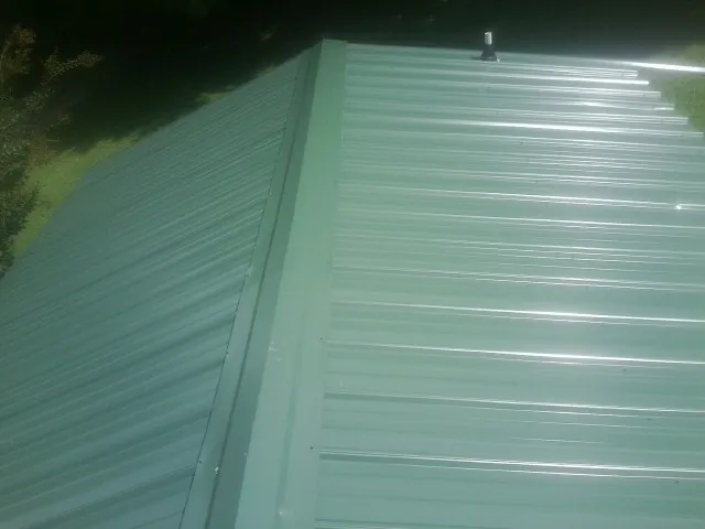 New green metal panels meeting at the ridge of a roof — Flat Roof Repair work by our crew in Yadkinville