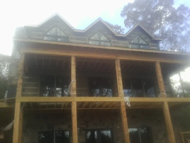 Dormers and porch framing on a large log home under construction — Roof Coating work by our crew in Yadkinville