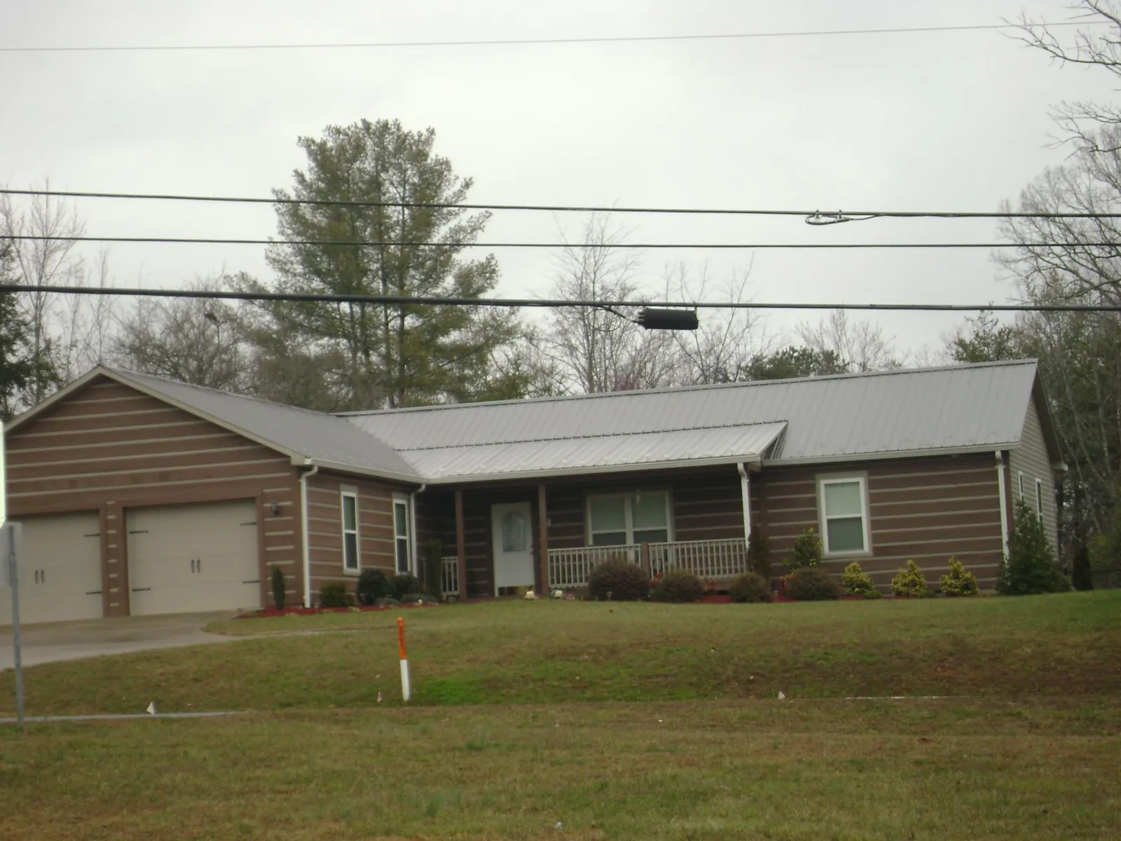 Gray metal roof on a log sided ranch home with a front porch in Yadkinville