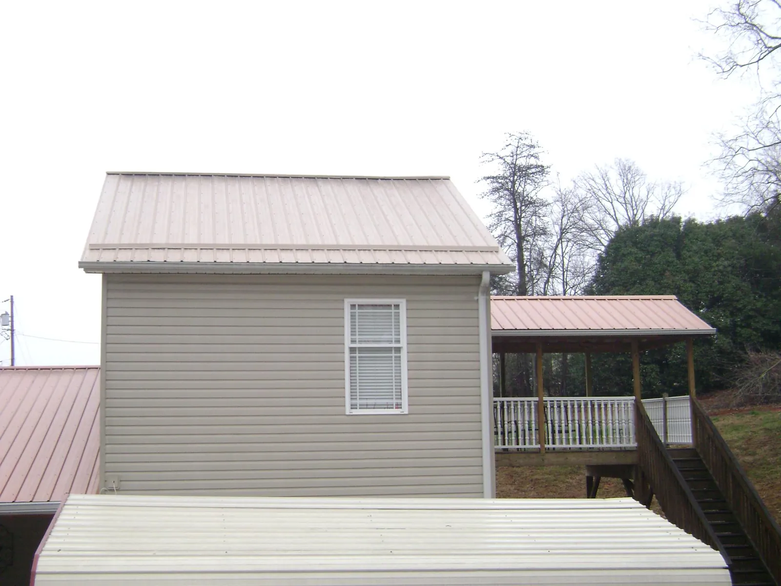 Tan metal roofs on a two story addition and attached porch, from a Roof Replacement job in Yadkinville