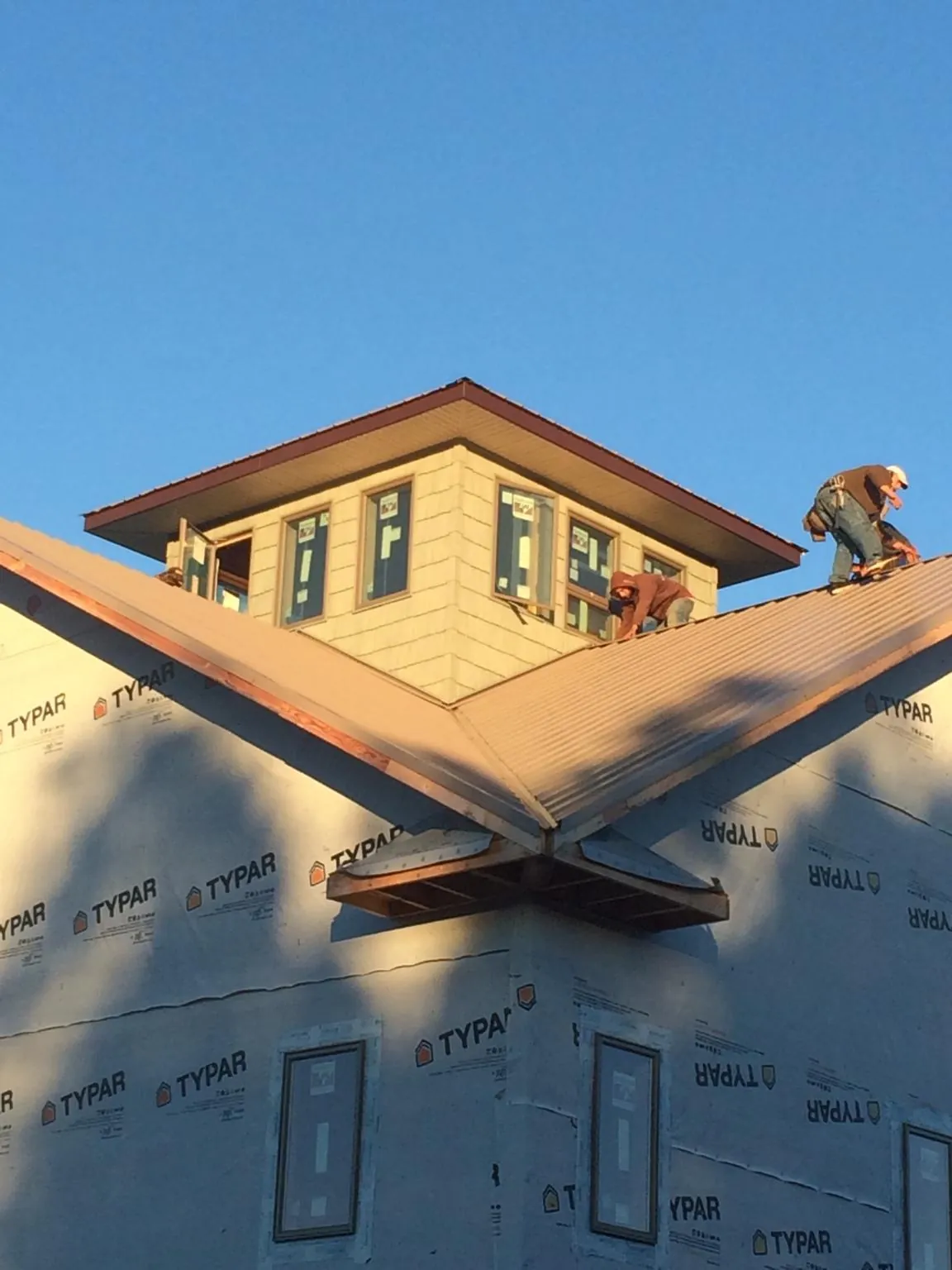 Roofers working around a rooftop cupola on a new metal roof at sunset — Roof Waterproofing in Yadkinville by Roofing Brothers